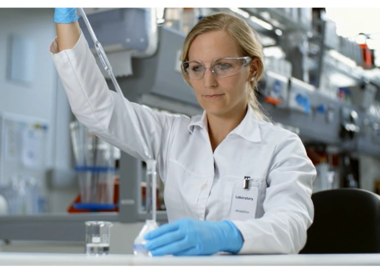 Female laboratory technician preparing a sample and performing precise volume measurement with a pipette.